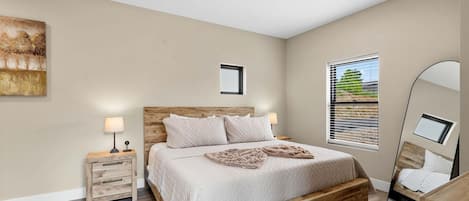 Une chambre à coucher avec un lit en bois, une table de chevet, une lampe de chevet et un grand miroir.