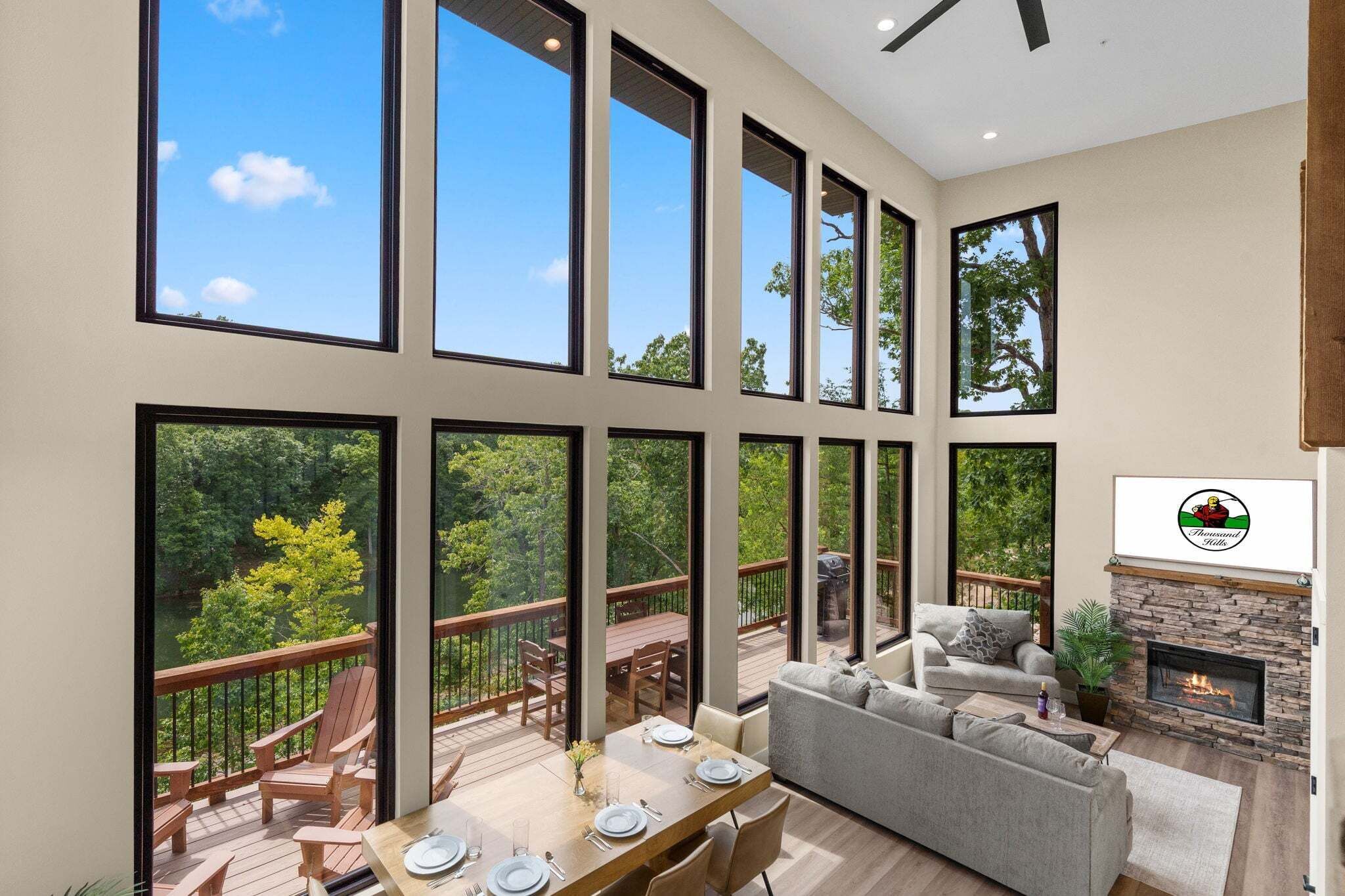 A spacious living area with a fireplace, large windows, and a deck with outdoor furniture.