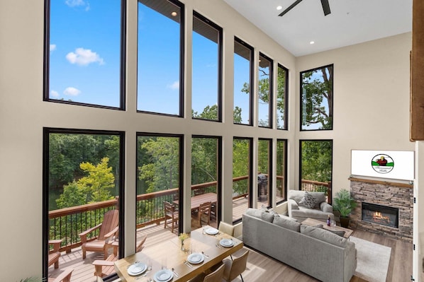 A spacious living area with a fireplace, large windows, and a deck with outdoor furniture.