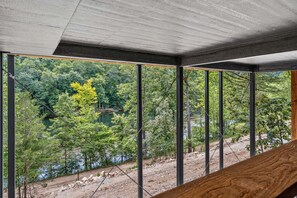 A room with a view of a forested area and a body of water.