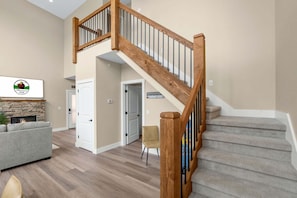 A spacious living area with a wooden staircase, a fireplace, and a couch.