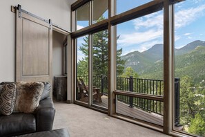 A room with a sliding glass door leading to a balcony with a mountain view. - Aspen Trail Retreat - Breathtaking Mountain Views! (Estes Park)