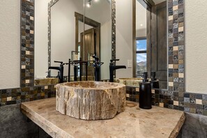 Ein Badezimmer mit großem Spiegel, einem Waschbecken aus Holz und einer gefliesten Rückwand.