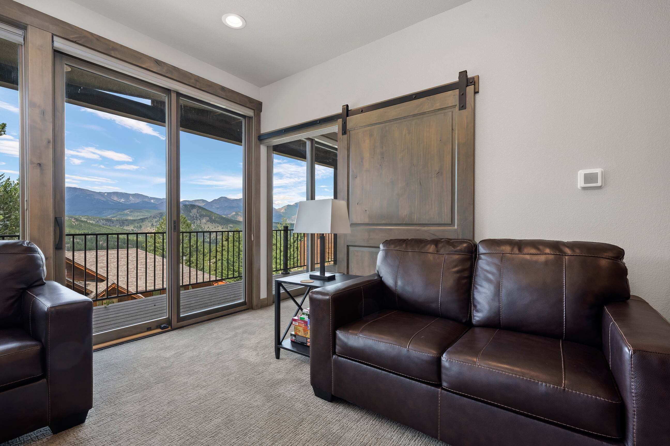Ein geräumiger Balkon mit Bergblick, ein Ledersofa und ein Tisch mit Lampe.