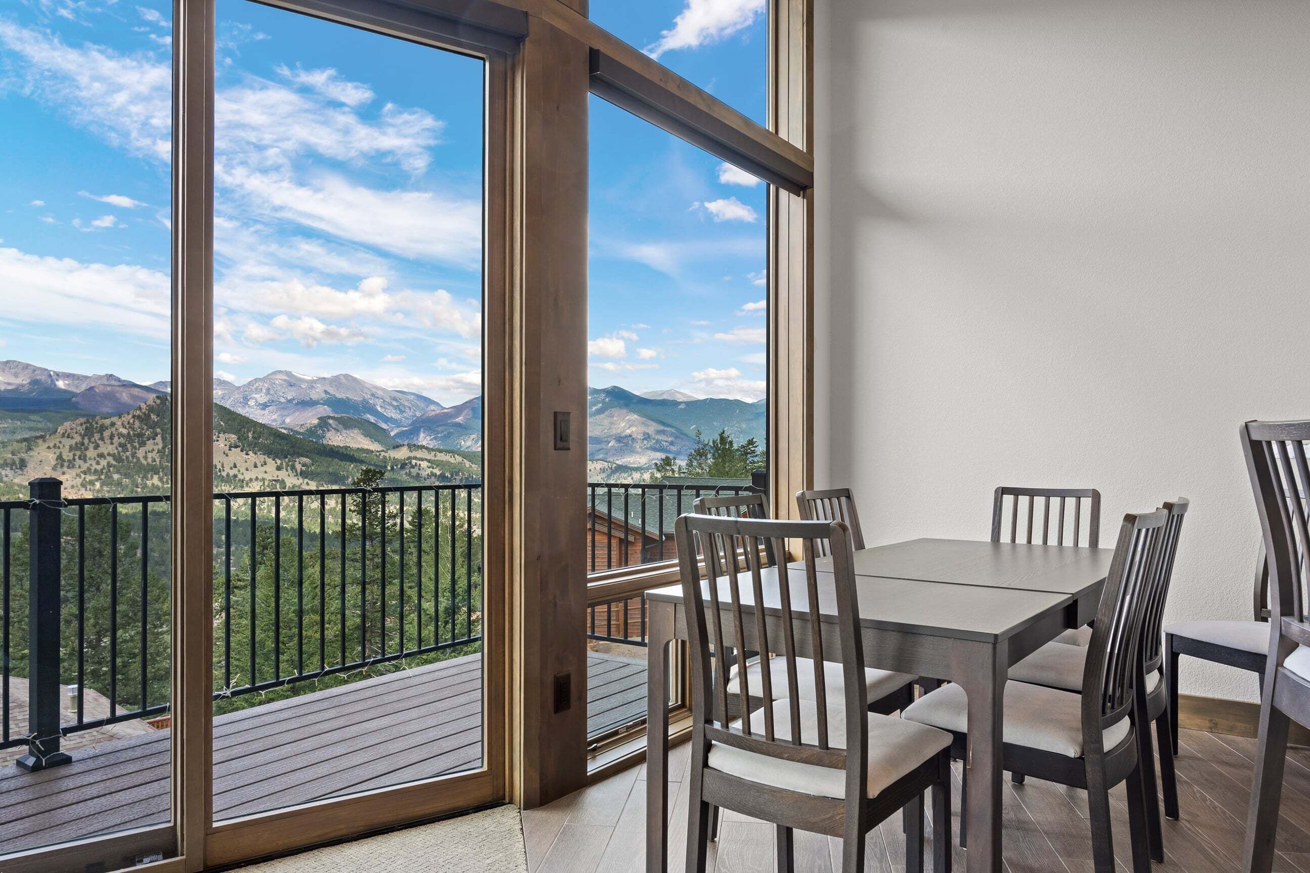 Ein Balkon mit Tisch und Stühlen, mit Blick auf eine gebirgige Landschaft.