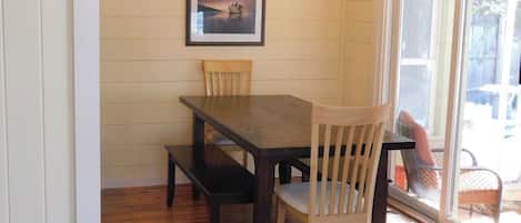 Un comedor con una mesa y sillas de madera, una araña y un cuadro en la pared.