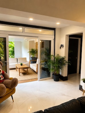 A modern living room with a sofa, a coffee table, and a large potted plant.