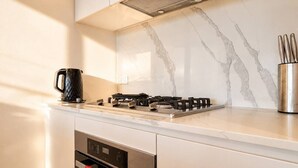 Una cocina moderna con estufa a gas, cafetera y un recipiente de acero inoxidable para utensilios.