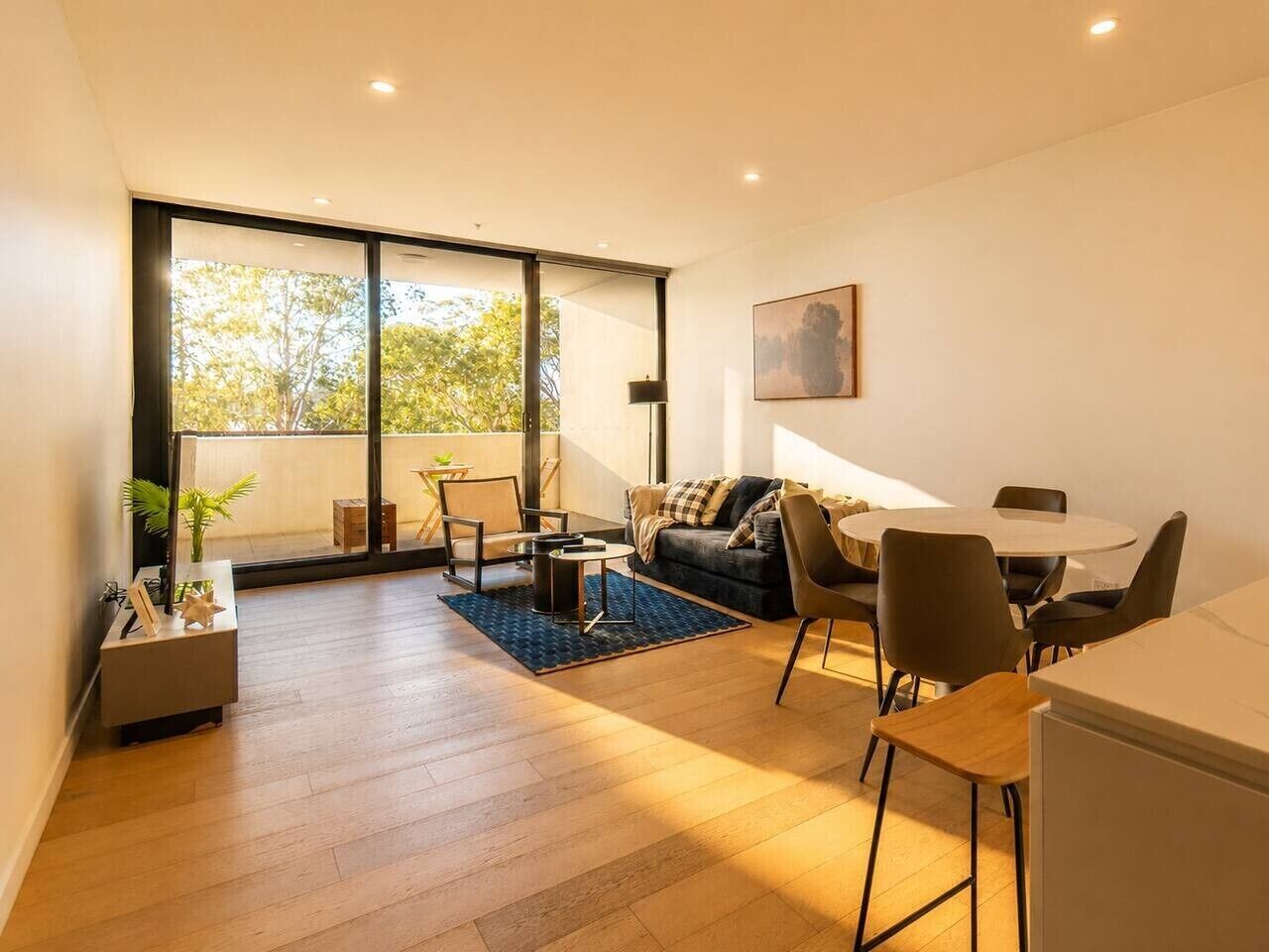 A modern living room with a sofa, chairs, a coffee table, and a dining area with a table and chairs.