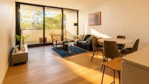Una sala de estar moderna con un sofá, sillas, una mesa de centro y un comedor con una mesa y sillas.