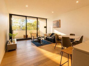 A modern living room with a sofa, chairs, a coffee table, and a dining area with a table and chairs. - Gordon 2BR Apt Walk to Station & Shops (Gordon)