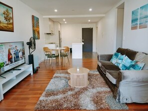Ein Wohnzimmer mit Fernseher, einer Couch, einem Couchtisch und einem Essbereich mit Stühlen und einem Tisch.