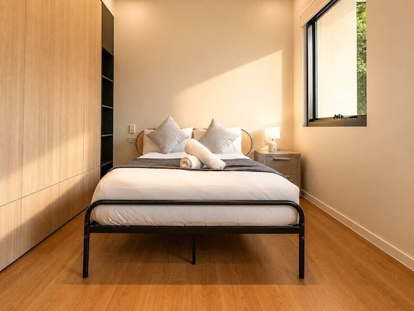 A modern bedroom with a bed, bedside tables, and a window.