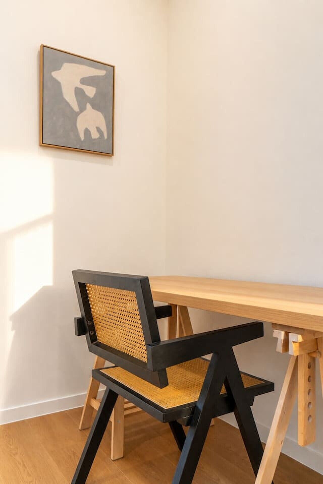 A corner room with a wooden desk and a black and brown chair.