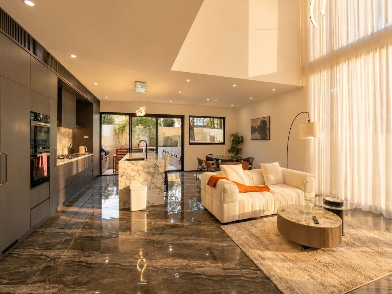 A modern living room with a sofa, coffee table, and a dining area with chairs.
