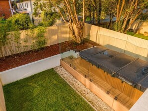 A rooftop with a flat surface, surrounded by a wooden deck and a glass enclosure.