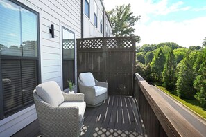 Ein Balkon mit zwei Korbstühlen und einer Holzterrasse.