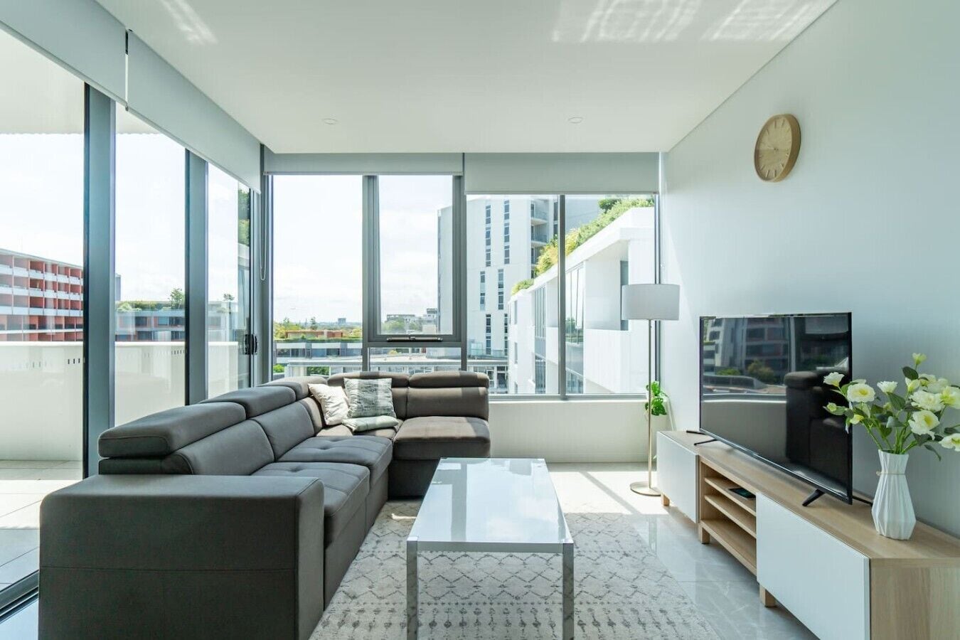 A modern living room with a sectional sofa, a flat-screen TV, and a minimalist coffee table.