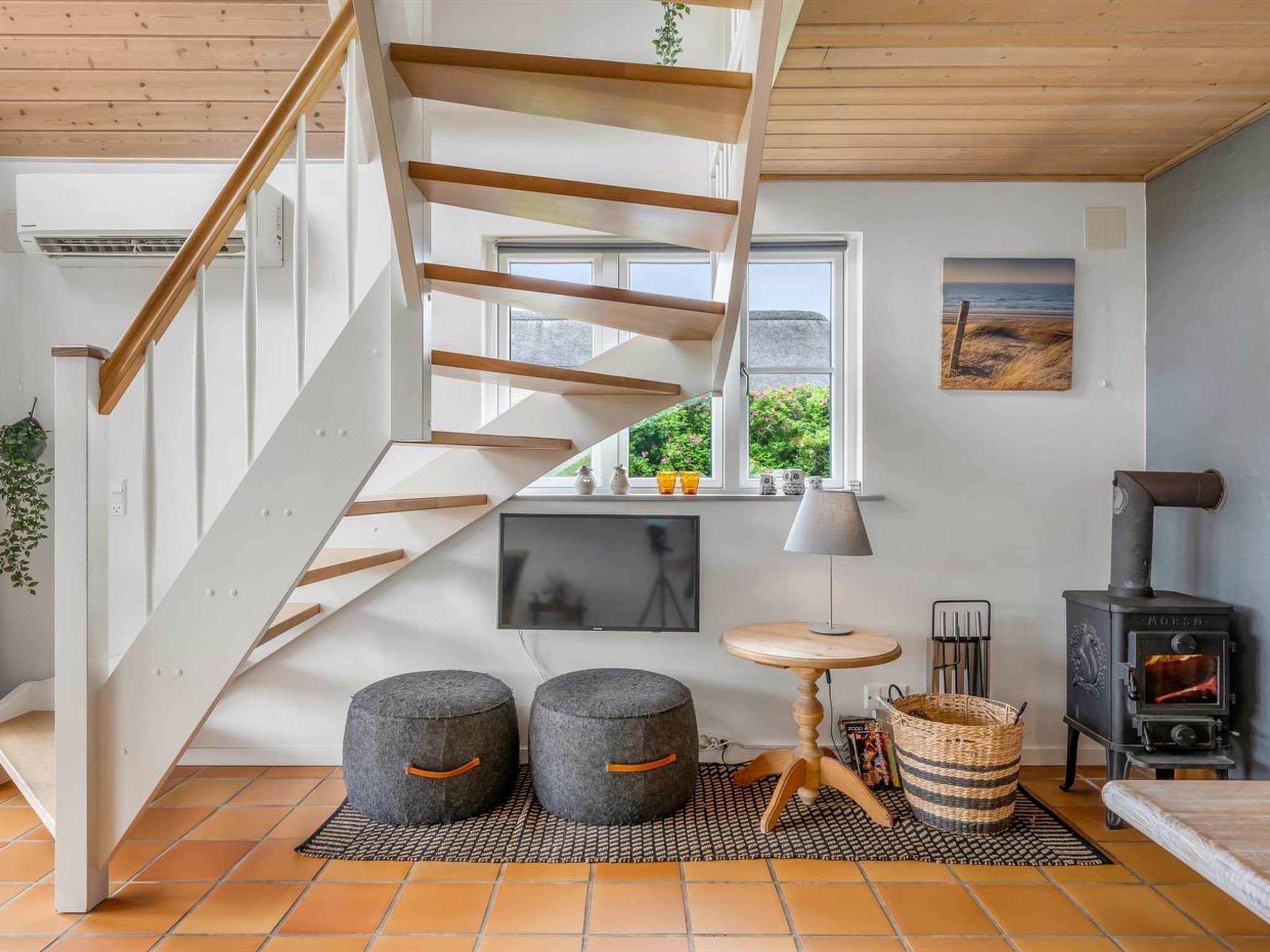 Un intérieur moderne avec un escalier en bois, une cheminée et une vue sur l’extérieur.