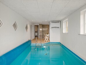 A swimming pool with a clear blue water, a shower area, and a seating area with chairs. - "Algut" - 200m from the sea by Interhome (Blåvand)