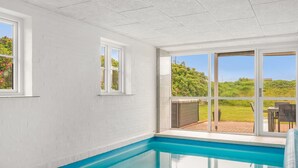 En pool med fri utsikt över omgivningen, en vit vägg och en dörr som leder ut.