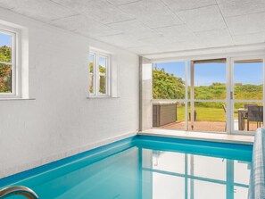 Ein Swimmingpool mit freiem Blick ins Freie, einer weißen Wand und einer Tür, die nach draußen führt.
