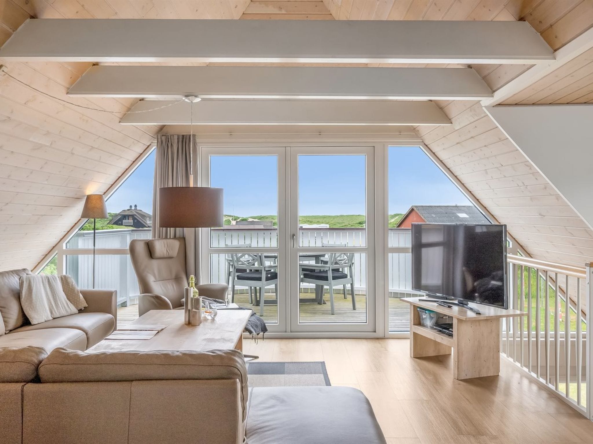Une chambre de style loft moderne, dotée d’une grande fenêtre, d’un canapé, d’un fauteuil, d’un téléviseur et d’une lampe.