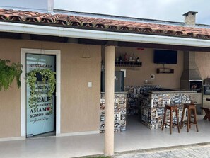 Ein Gebäude mit überdachtem Außenbereich, einer Bar mit Hockern und einem Schild an der Tür.