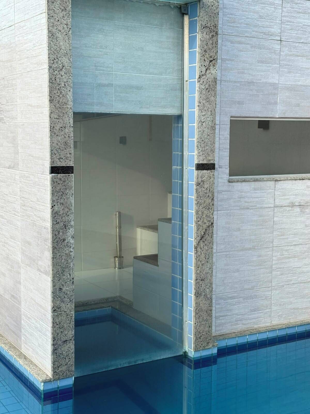A modern bathroom with a glass shower enclosure, a visible showerhead, and a tiled floor.