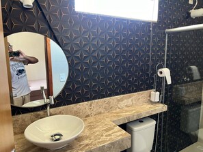 Une salle de bain avec un miroir rond, un lavabo et un espace douche.