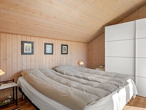 A bedroom with a wooden ceiling, a bed with a grey duvet, a bedside table with a lamp, and framed pictures on the wall. - "Aida" - 550m from the sea by Interhome (Esbjerg V)