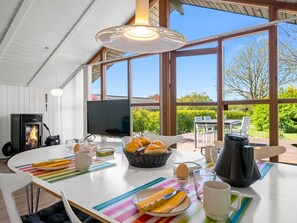 A modern kitchen with a fireplace, large windows, and a dining area with outdoor seating. - "Aida" - 550m from the sea by Interhome (Esbjerg V)