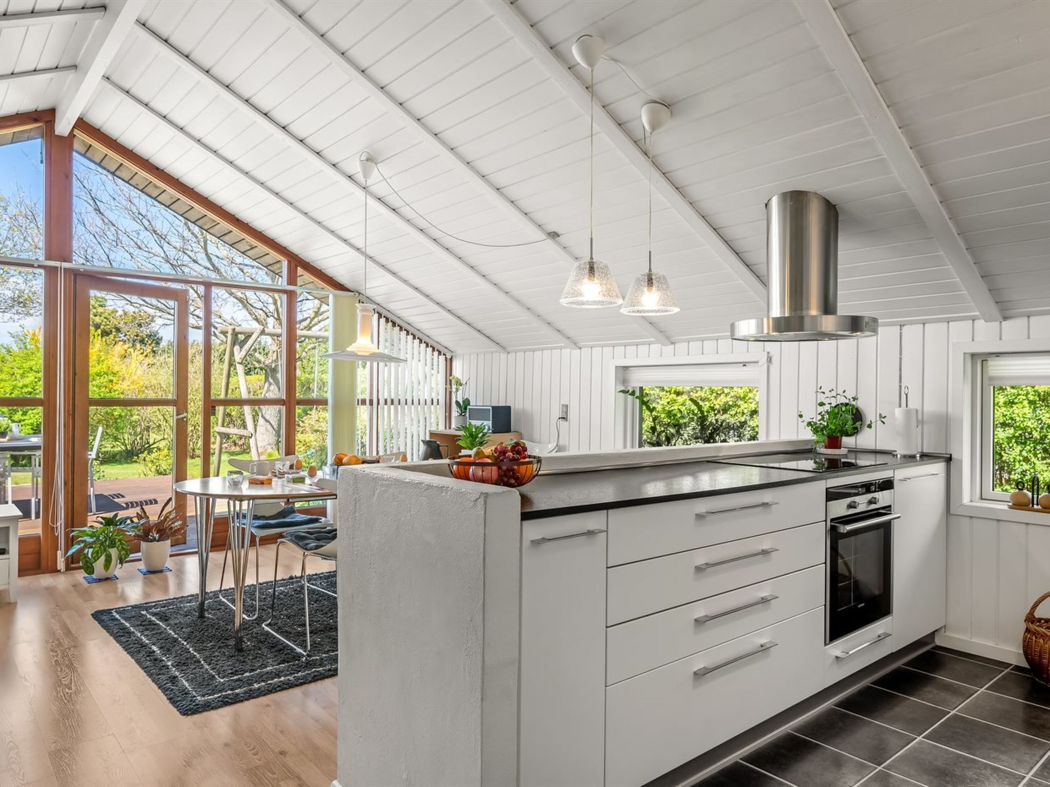 A modern kitchen with a large island, white cabinetry, and a stainless steel range hood.