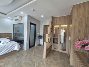 Ein Hotelzimmer mit Bett, begehbarem Kleiderschrank, Ventilator und Dusche.