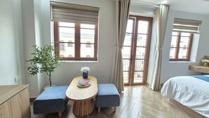 A hotel room with a wooden floor, a bed, a dining table with two blue benches, a potted plant, and a view through the glass doors. - LANA SEA (An Thoi)