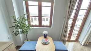 A dining area with a wooden table, two blue cushioned benches, a potted plant, and a window with a view of buildings. - LANA SEA (An Thoi)