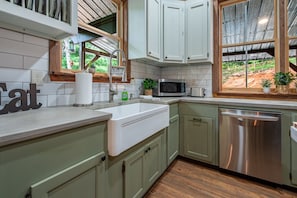 A kitchen with a sink, microwave, and stainless steel dishwasher. - Firefly Retreat - Upscale Off-Grid Mountain Cabin (Marble Hill)