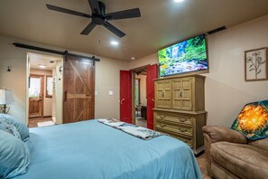 A bedroom with a bed, a dresser, a television, and a ceiling fan.