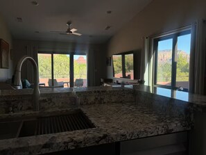Una cocina con encimera de granito, un fregadero y un ventilador de techo.