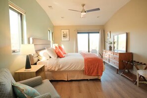 Ein Schlafzimmer mit einem Bett, Nachttischen, einem Sessel, einer Kommode und einem Deckenventilator.