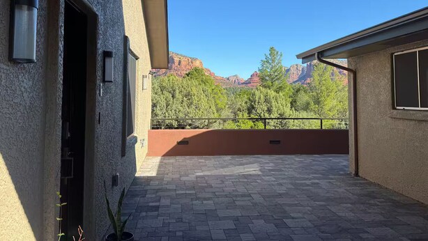 Ein Gebäude mit einer Terrassenfläche, einer Tür und Blick auf Berge.