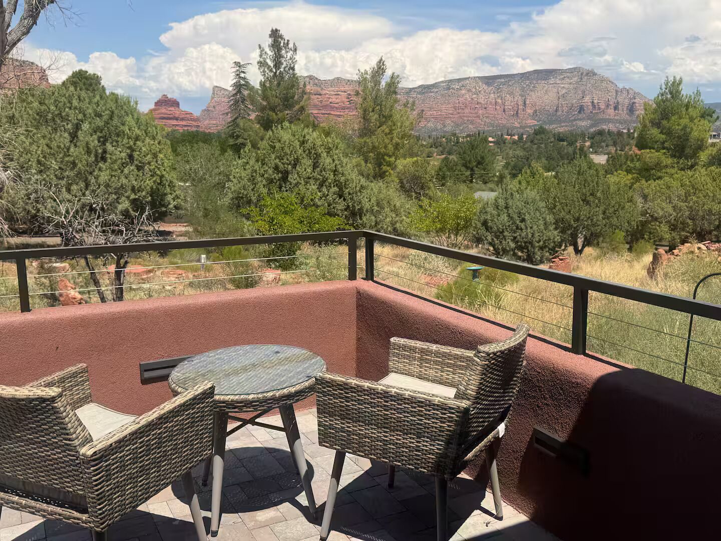 Un patio exterior con mobiliario de mimbre y vistas a formaciones rocosas rojas.
