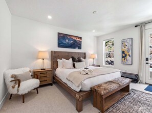 A bedroom with a wooden bed, bedside tables, a chair, and artwork on the walls. - Mountain Haus, Hot Tub, Sauna, Deer Valley Close (Heber City)
