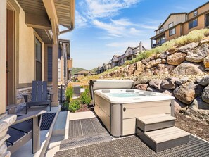 A hot tub with steps leading up to it, surrounded by a stone wall and a patio area with outdoor furniture. - Mountain Haus, Hot Tub, Sauna, Deer Valley Close (Heber City)