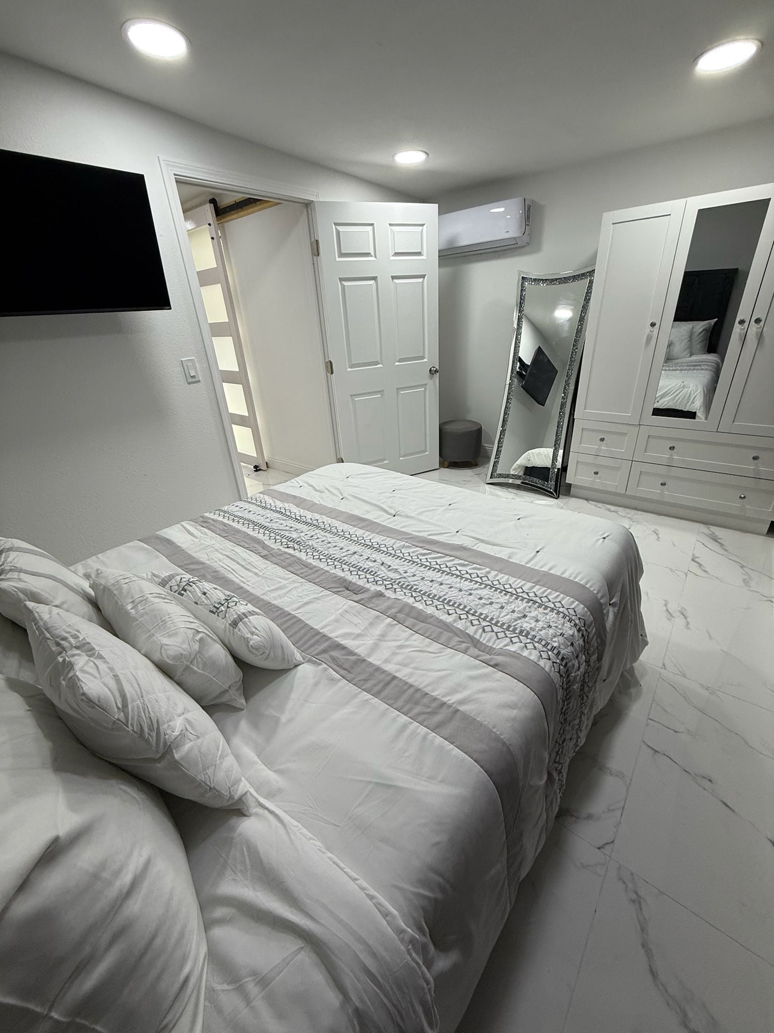 A bedroom with a bed, a wardrobe, a mirror, and a door.