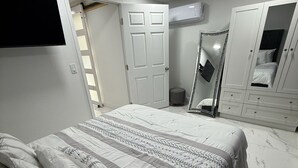 A bedroom with a bed, a wardrobe, a mirror, and a door.