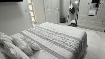 A bedroom with a bed, a wardrobe, a mirror, and a door.