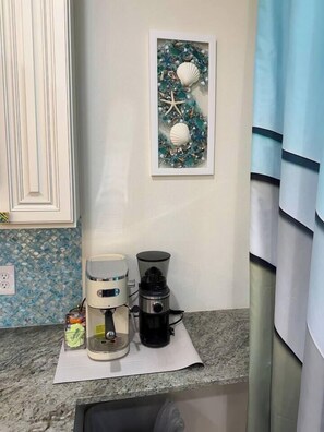 Eine Küchenarbeitsplatte mit einer Kaffeemaschine, einem Wasserkocher und einer Kapselbox für Kaffee.