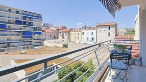 Uma varanda com vista para uma área residencial, grade de metal e planta em vaso.