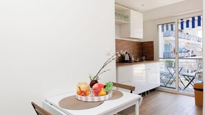 Uma cozinha moderna com armários brancos, bancada de madeira e vista para uma varanda com móveis de exterior.